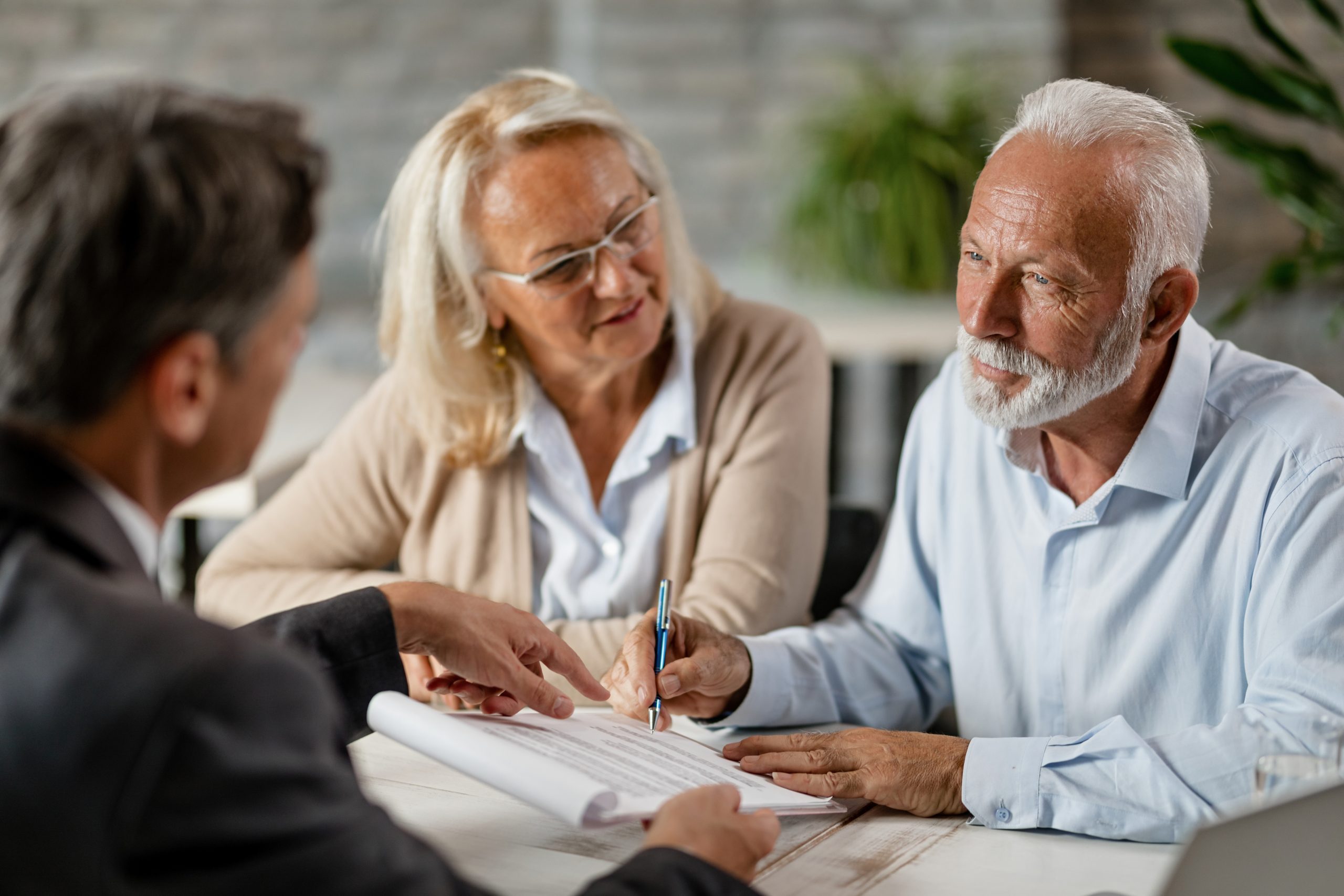 Senior couple signing a contract while having a meeting with ins asesoramiento contable